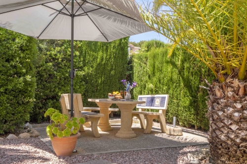 Stenen tuintafel met parasol onder een palmboom