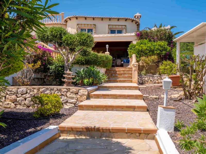 Tuinpad met flagstones, bougainville en het villaterras op de achtergrond
