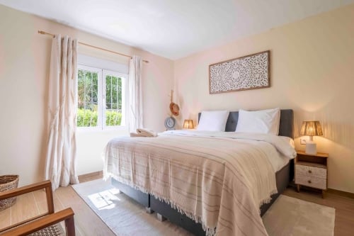 Slaapkamer met tweepersoonsbed, gordijnen en wanddecoratie